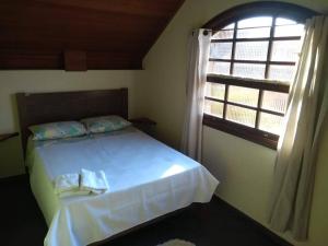 una camera da letto con un letto bianco con una finestra di Casa Vivenda dos Bem-te-vis a Monte Verde