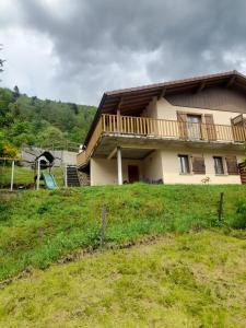 a house on top of a grassy hill at Grand gîte du Bruleux 11 personnes in La Bresse