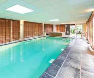 a large swimming pool with blue water in a building at ibis Styles Morlaix in Morlaix