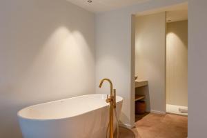 een badkamer met een bad en een witte muur bij Huswell - Luxurious apartment on top location in Knokke in Knokke-Heist