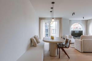 een witte woonkamer met een tafel en een bank bij Huswell - Luxurious apartment on top location in Knokke in Knokke-Heist