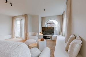 een witte woonkamer met een bank en een tv bij Huswell - Luxurious apartment on top location in Knokke in Knokke-Heist +35 foto's