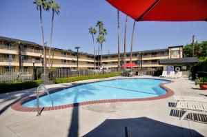 a swimming pool with an umbrella and a building at Vagabond Inn Whittier in Whittier