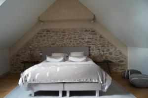 a bedroom with a bed with a stone wall at Les Grands Gîtes de Cancale, gîtes de charme avec jacuzzi in La Coudre