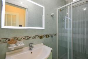 Un baño con lavabo, espejo y ducha. en Appartamenti America, en Sirmione