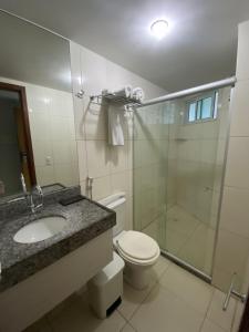 a bathroom with a toilet and a glass shower at Blue Sunset Suites in Penha