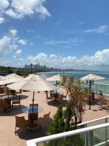 a patio with tables and umbrellas and the ocean at Blue Sunset Suites in Penha