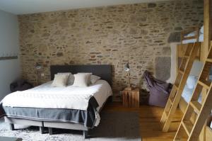a bedroom with a bed and a stone wall at Les Grands Gîtes de Cancale, gîtes de charme avec jacuzzi in La Coudre