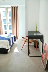 a bedroom with a bed and a table and a window at Waterview apartments with ultra fast wifi close to Excel and O2, corporates and contractors welcome in London