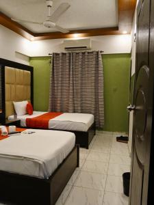 two beds in a room with green walls at Hometown Apartments & Rooms in Karachi