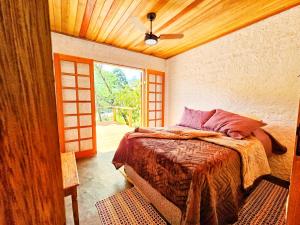 Un dormitorio con una cama y un ventilador de techo. en Casinha da Mantiqueira - SAP, en Santo Antônio do Pinhal