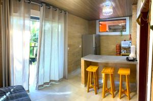 a kitchen with a counter with stools and a refrigerator at Jacarecica Haus in Maceió