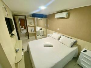 a small bedroom with a white bed and a mirror at JT Manaíra Palace in Tambaú