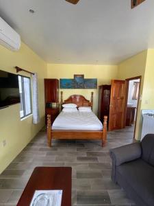 ein Schlafzimmer mit einem Bett und einer Couch in der Unterkunft Hidden Treasure Vacation Home Lagoona bay cottage in Caye Caulker