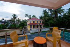 a balcony with two chairs and a table and a house at Lykke Suites- 2-min Drive to Colva Beach-By Goan Felicidade Hospitality PVT LTD in Colva