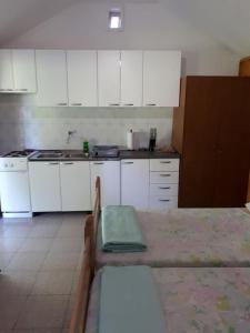 a kitchen with white cabinets and a table in it at House Lidija in Postira +11 photos