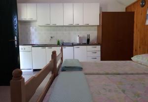 a kitchen with white cabinets and a bed in a room at House Lidija in Postira