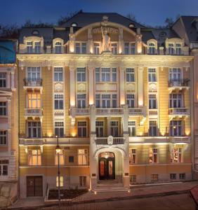 Un grand bâtiment jaune avec ses lumières allumées dans l'établissement Luxury Spa Hotel Olympic Palace, à Karlovy Vary