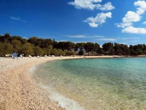 a beach with white chairs and the blue water at Apartments Brti in Supetar