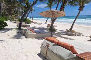 a beach with chairs and an umbrella and the ocean at The Beach Tulum Hotel in Tulum