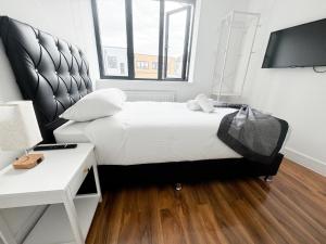 Un dormitorio con una cama, un escritorio y un televisor. en Centra Palmers Green, en Londres 6 fotos más