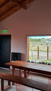 a wooden table in a room with a large window at Guanaco Inn in El Calafate