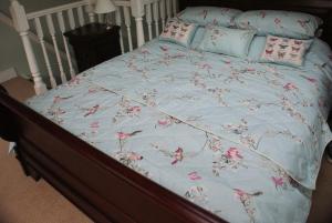 a bed with a blue comforter with pink flowers on it at The Sewing Room in Hebden Bridge