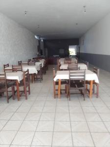 a dining room with white tables and wooden chairs at Minas Hotel in Alcobaça