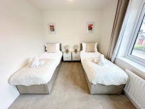 Dos camas individuales en una habitación con ventana. en Luxury 2 Bed - FREE Private Parking - Contractors, en Newcastle