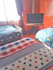 a room with two beds and a desk with a computer at Hostel Adriana in Valdivia +2 photos
