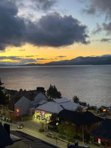 a view of a city and the water with a sunset at Depto. Quelo in San Carlos de Bariloche