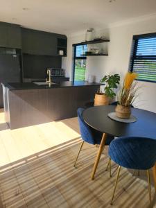 a kitchen with a black table and blue chairs at Kotuku Cottage in Tauranga