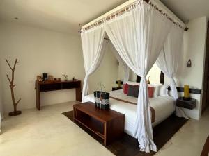 a bedroom with a canopy bed with a wooden table at The Beach Tulum Hotel in Tulum