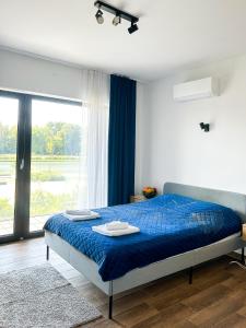 a bedroom with a bed with blue sheets and a window at Aquarius Stawy 1 in Grodzisk Mazowiecki