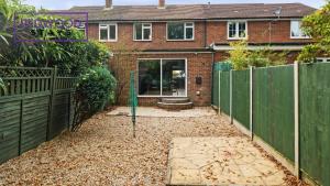 a garden with a fence and a house at 3 BEDROOM SERVICED HOUSE WITH FREE PARKING FOR 2 CARS, FREE WiFi, PERFECT FOR BUSINESS STAYS, FAMILIES, RELOCATIONS, EXTENDED STAYS, AND EMERGENCY ACCOMMODATION by REDWOOD STAYS in Camberley