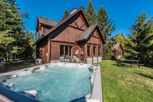a large hot tub in front of a log house at Chalets Royal Laurentien in Saint-Faustin