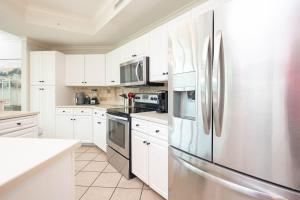 a kitchen with white cabinets and a stainless steel refrigerator at Phoenix on the Bay 1414 condo in Orange Beach