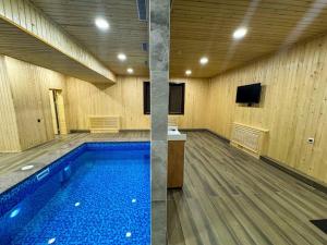 a large swimming pool in a room with a television at DOSTYK Hotel in Zyryanovsk