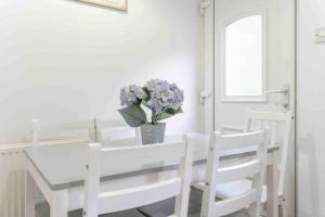 Una mesa de comedor blanca y sillas con un jarrón de flores. en Glentarbet House, en Glasgow