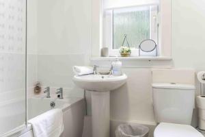 Un baño blanco con lavabo e inodoro. en Glentarbet House, en Glasgow 21 fotos más