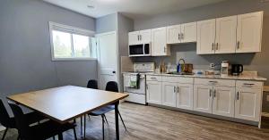 a kitchen with white cabinets and a table with chairs at Central Thunder Bay Retreat in Thunder Bay