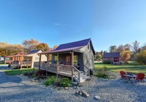 a small cabin with a porch and a table and chairs at Cozy Cub at Deep Creek in Bryson City