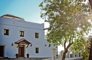 un edificio blanco con un árbol delante en Alojamiento Rural El Lario, en Alcalá de los Gazules