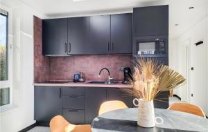 eine Küche mit schwarzen Schränken und einem Tisch mit Stühlen in der Unterkunft Gorgeous Home In Heinkenszand With Wifi in Heinkensand