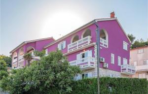 un bâtiment rose avec des balcons blancs et un arbre dans l'établissement Amazing Apartment In Mundanije, à Mundanije