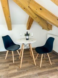 two chairs and a table in a room with wooden ceilings at Aquarius Stawy 11 in Grodzisk Mazowiecki