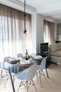 a dining room with a glass table and white chairs at Lux Downtown Sea View Apartment D3 in Thessaloniki