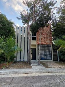 a building with a tree in front of it at Casa Balam en Puerto Morelos in Puerto Morelos