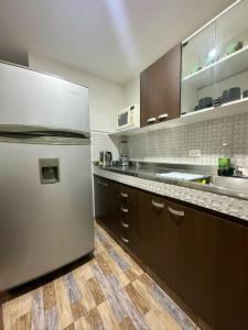 a kitchen with a stainless steel refrigerator and wooden cabinets at Apartamento en Envigado al Sur de Medellin in Envigado +12 photos