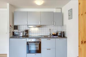 a kitchen with white cabinets and a stove top oven at Studio - Modernes Design nahe Müritzstrand & Wellness in Waren +13 photos